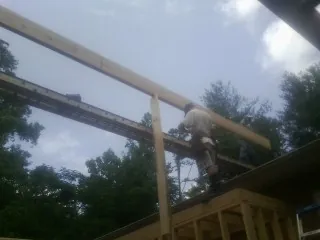 Carpenter setting a ridge beam over a new addition frame — Ice Dam Removal by Roofing Brothers in Coyle