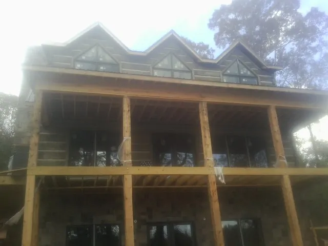 Dormers and porch framing on a large log home under construction — Roof Coating work by our crew in Coyle