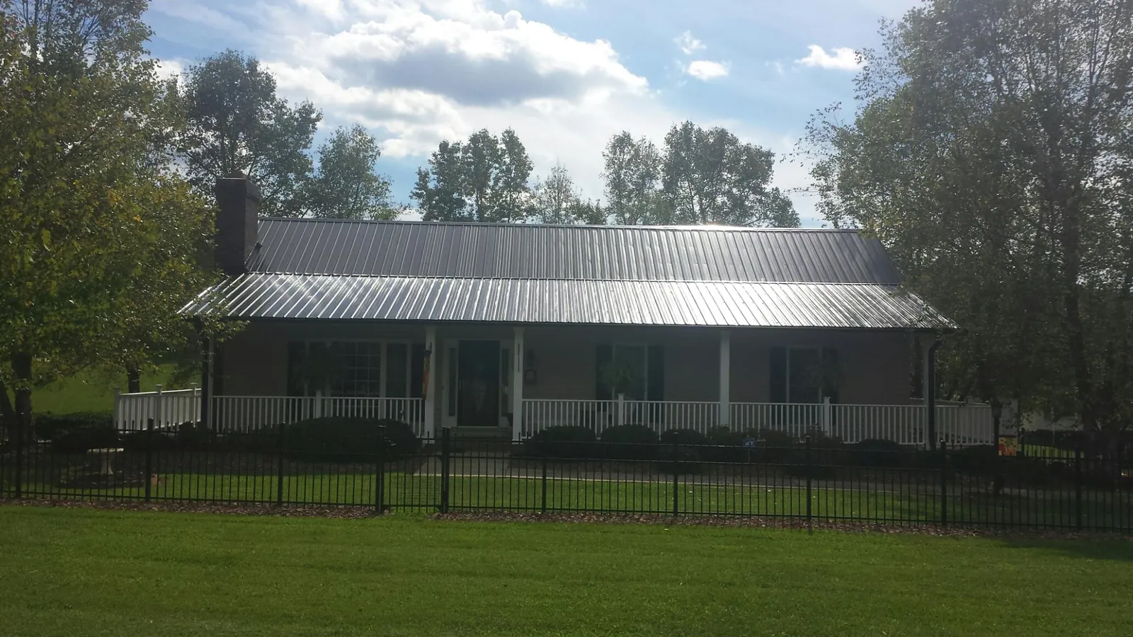 Gray metal roof on a brick ranch with a full width front porch — Gutter Guard Installation work by our crew in Coyle